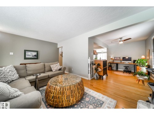 Open-concept living area featuring wood-finish flooring, a neutral color palette, and a ceiling fan with light fixture - 10231 46 Street, Edmonton, AB 