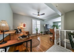Bright interior space featuring wood-finish flooring, a contemporary ceiling fan, and white window shutters - 