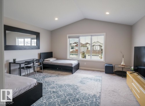 Spacious room featuring a vaulted ceiling with recessed lighting, a large window providing ample natural light, and plush carpeting - 1728 53 Street, Edmonton, AB - Indoor