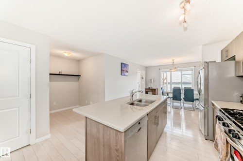 Kitchen featuring an island with double sink and light countertop, stainless steel appliances, and wood-finish flooring - 328 Watt Boulevard, Edmonton, AB - Indoor Photo Showing Kitchen With Double Sink