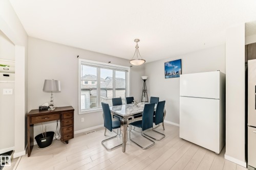 Bright dining area featuring wood-finish flooring, a contemporary ceiling light fixture, a large window with white trim, and light-toned wall paint - 328 Watt Boulevard, Edmonton, AB - Indoor Photo Showing Dining Room