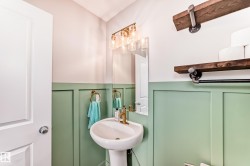 Pedestal sink with brass-finish faucet, framed by a wall-mounted mirror and a three-light vanity fixture - 