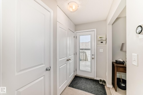 Entryway featuring a glass-paned exterior door, built-in storage cabinets, neutral wall paint, and light-toned flooring - 328 Watt Boulevard, Edmonton, AB - Indoor Photo Showing Other Room