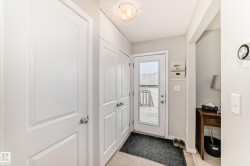 Entryway featuring a glass-paned exterior door, built-in storage cabinets, neutral wall paint, and light-toned flooring - 