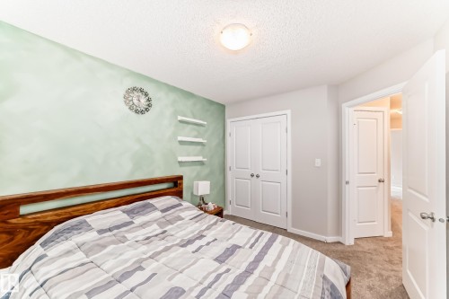 Bedroom featuring a wood-finish headboard, a light green accent wall, and three wall-mounted shelves - 328 Watt Boulevard, Edmonton, AB - Indoor Photo Showing Bedroom