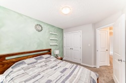 Bedroom featuring a wood-finish headboard, a light green accent wall, and three wall-mounted shelves - 