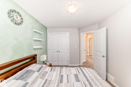 Carpeted room featuring a light green accent wall with three built-in floating shelves, white trim, and a ceiling-mounted light fixture - 328 Watt Boulevard, Edmonton, AB - Indoor Photo Showing Bedroom