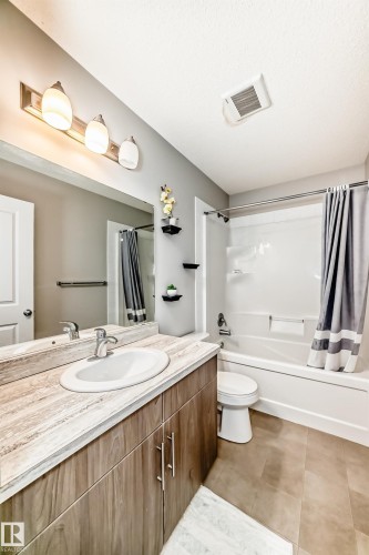 Bathroom featuring a wood-finish vanity with a single basin sink and a light-toned countertop - 328 Watt Boulevard, Edmonton, AB - Indoor Photo Showing Bathroom