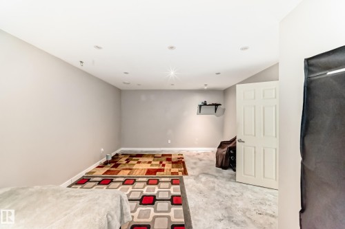 Spacious interior room featuring light gray walls, recessed ceiling lighting, and a white six-panel door with silver hardware - 328 Watt Boulevard, Edmonton, AB - Indoor