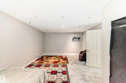 Spacious interior room featuring light gray walls, recessed ceiling lighting, and a white six-panel door with silver hardware - 