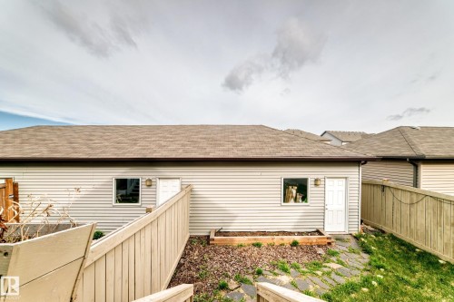 Rear exterior showcasing light-toned horizontal siding, a brown shingle roof, and a discrete access door - 328 Watt Boulevard, Edmonton, AB - Outdoor