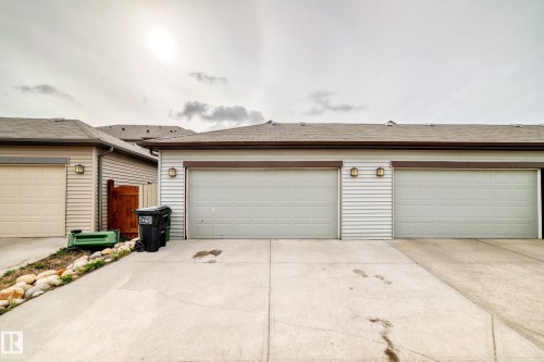 Three attached garages with light-colored garage doors and exterior wall sconces - 328 Watt Boulevard, Edmonton, AB - Outdoor With Exterior
