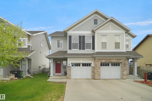 Two-story home with a two-car garage, stone veneer accents, and a red entry door - 1702 Chapman Way, Edmonton, AB - Outdoor With Facade