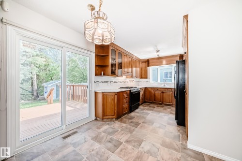 Kitchen featuring warm wood cabinetry, neutral tile flooring, white countertops, and a full suite of black appliances - 79 Broadview Crescent, St. Albert, AB - Indoor Photo Showing Other Room