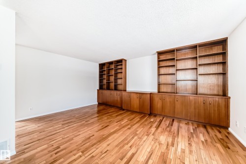 Expansive interior space featuring rich wood-finish flooring, built-in shelving, and integrated lower cabinetry - 79 Broadview Crescent, St. Albert, AB - Indoor Photo Showing Other Room