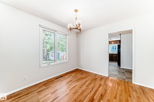 Open-concept room featuring wood-finish flooring, a white window frame, and a gold-tone chandelier with glass shades - 79 Broadview Crescent, St. Albert, AB - Indoor Photo Showing Other Room