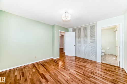 Light-filled room featuring wood-finish flooring, a contemporary ceiling fixture, and a full wall of bi-fold louvered doors - 79 Broadview Crescent, St. Albert, AB - Indoor Photo Showing Other Room