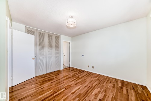 Wood-finish flooring throughout, featuring a multi-panel louvered closet system and a ceiling-mounted light fixture - 79 Broadview Crescent, St. Albert, AB - Indoor Photo Showing Other Room