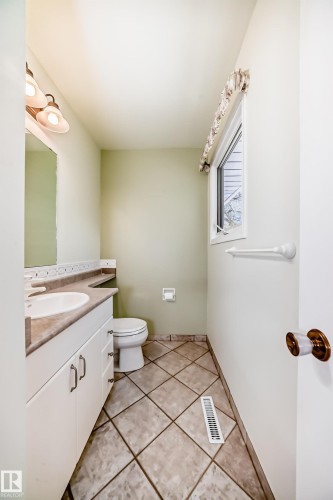 Bathroom featuring a single vanity with an integrated sink, a commode, and a window for natural light - 79 Broadview Crescent, St. Albert, AB - Indoor Photo Showing Bathroom