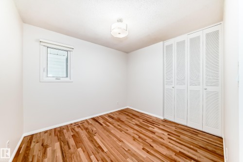 Bright room featuring wood-finish flooring, white walls, louvered bi-fold closet doors, and a single window with a roller shade - 79 Broadview Crescent, St. Albert, AB - Indoor Photo Showing Other Room