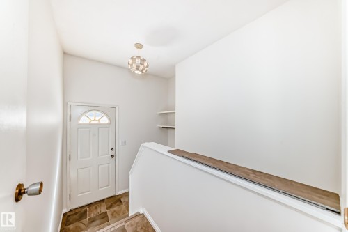 Entryway featuring a paneled door with an arched window, a geometric pendant light fixture, and built-in shelving - 79 Broadview Crescent, St. Albert, AB - Indoor Photo Showing Other Room
