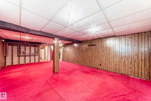 Spacious room with red carpeting, wood paneling, a drop ceiling with recessed lighting, and visible structural beams - 79 Broadview Crescent, St. Albert, AB - Indoor Photo Showing Other Room