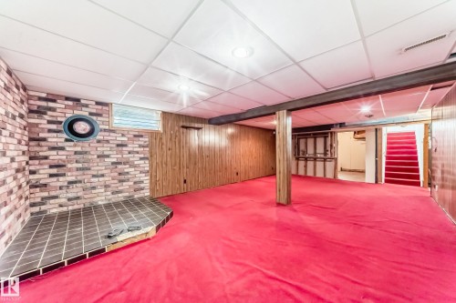Spacious lower level featuring brick-style wall, wood paneling, recessed lighting, and a tiled hearth - 79 Broadview Crescent, St. Albert, AB - Indoor