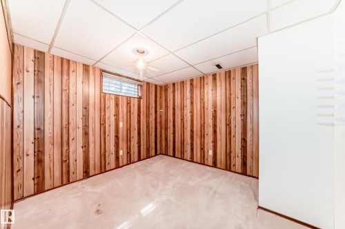 Carpeted room featuring wood-paneled walls, a drop ceiling, and a single window with blinds - 79 Broadview Crescent, St. Albert, AB - Indoor Photo Showing Other Room