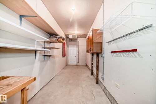 Utility room featuring extensive wall-mounted shelving, overhead storage racks, built-in cabinetry, exposed conduit, and a concrete floor - 79 Broadview Crescent, St. Albert, AB - Indoor