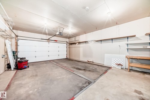 Spacious garage with a sectional overhead door, overhead lighting, and concrete flooring - 79 Broadview Crescent, St. Albert, AB - Indoor Photo Showing Garage