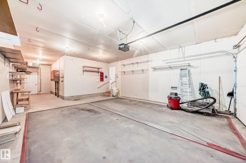 Spacious garage featuring a concrete floor, overhead lighting, integrated shelving, and a prominent garage door track system - 79 Broadview Crescent, St. Albert, AB - Indoor Photo Showing Garage