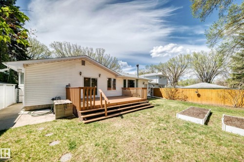 Spacious backyard featuring a multi-level wooden deck, a light-colored privacy fence, and two raised garden beds - 79 Broadview Crescent, St. Albert, AB - Outdoor With Deck Patio Veranda With Exterior