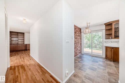 Interior space featuring wood-finish flooring, built-in shelving, tiled flooring, a brick accent wall, and sliding glass doors - 79 Broadview Crescent, St. Albert, AB - Indoor Photo Showing Other Room With Fireplace