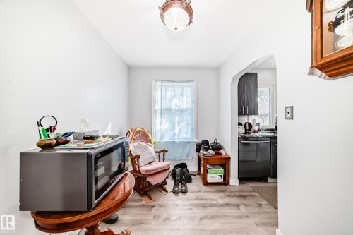 Light wood-finish flooring extending from the foreground into an arched doorway - 11303 60 Street, Edmonton, AB - Indoor Photo Showing Other Room