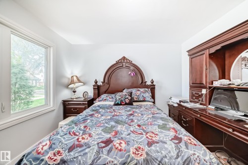 Bedroom featuring a single window with white trim, light-colored walls, and a built-in wood desk unit with storage cabinetry - 11303 60 Street, Edmonton, AB - Indoor Photo Showing Bedroom
