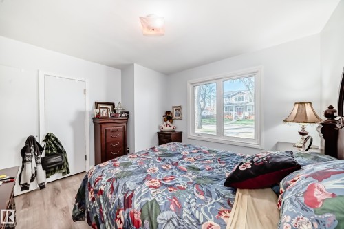 Light-filled room featuring wood-finish flooring, white walls, and a prominent window - 11303 60 Street, Edmonton, AB - Indoor Photo Showing Bedroom