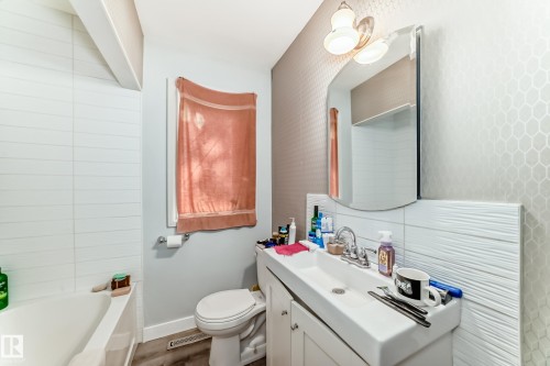 Bathroom featuring a built-in bathtub, a window, a toilet, a vanity with an integrated sink, and an overhead light fixture - 11303 60 Street, Edmonton, AB - Indoor Photo Showing Bathroom