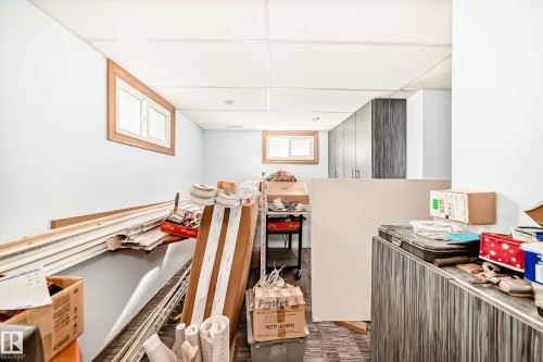 Recessed lighting illuminates a space featuring light blue walls, wood-framed windows, and built-in cabinetry with a dark wood-finish - 11303 60 Street, Edmonton, AB - Indoor Photo Showing Other Room
