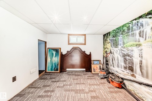 Room featuring patterned carpet flooring, a drop ceiling, and a window with wood trim - 11303 60 Street, Edmonton, AB - Indoor Photo Showing Other Room