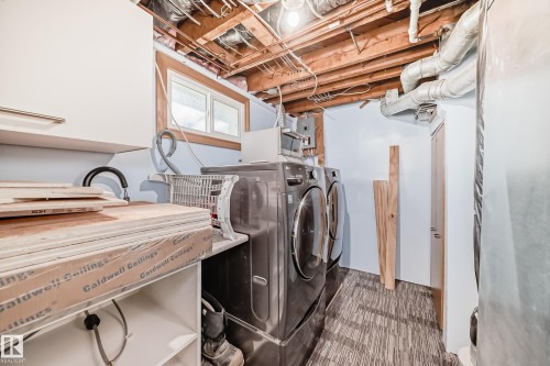 Laundry area featuring a side-by-side washer and dryer, white cabinetry, and wood-finish flooring - 11303 60 Street, Edmonton, AB - Indoor Photo Showing Laundry Room