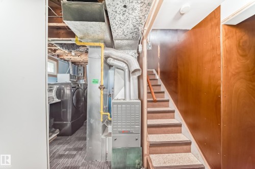 Utility area featuring a furnace, exposed ductwork, and a laundry station with a washer and dryer - 11303 60 Street, Edmonton, AB - Indoor