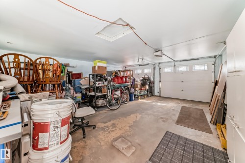 Two-car garage featuring segmented overhead doors with transom windows, a concrete floor, and built-in storage cabinetry - 11303 60 Street, Edmonton, AB - Indoor Photo Showing Garage