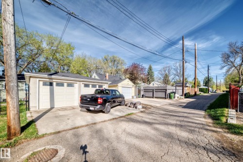 Detached two-car garage with panel garage doors and integrated windows, featuring a concrete driveway and an additional single-car garage in the background - 11303 60 Street, Edmonton, AB - Outdoor