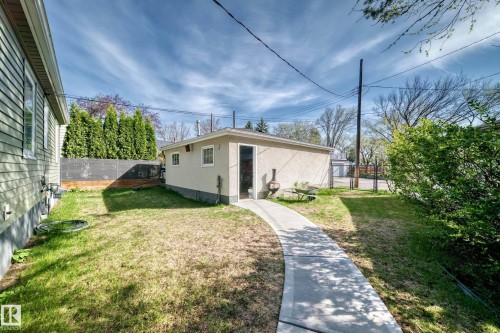 Detached rear garage with stucco exterior and dual windows, accessible via a curved concrete walkway - 11303 60 Street, Edmonton, AB - Outdoor