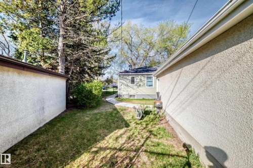 Manicured lawn area with a winding paved pathway leading to a detached structure featuring light-colored siding and a dark shingled roof - 11303 60 Street, Edmonton, AB - Outdoor