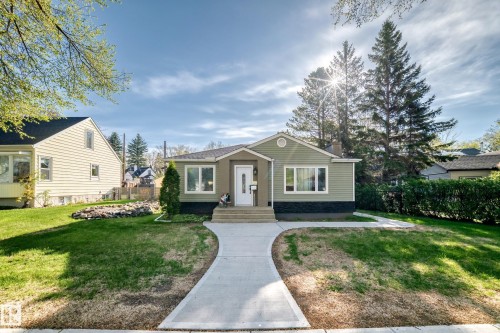 Ranch-style residence featuring light green siding, dark trim, a white entry door, and multiple front-facing windows - 11303 60 Street, Edmonton, AB - Outdoor With Facade