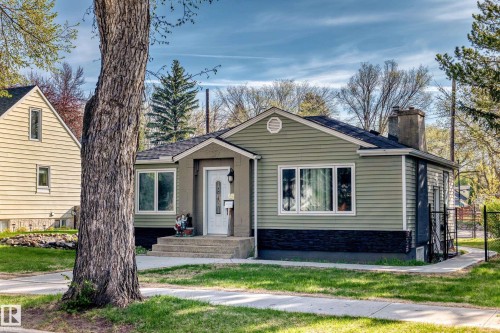 Single-story residence featuring light green horizontal siding and a contrasting dark lower facade - 11303 60 Street, Edmonton, AB - Outdoor