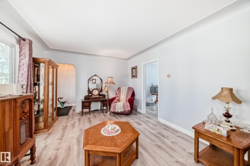 Spacious room featuring light-toned wood-finish flooring, crisp white baseboards, and neutral wall paint - 11303 60 Street, Edmonton, AB - Indoor