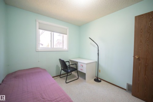 Interior room featuring a single window, light-colored carpeting, and a wood-finish door - 4724 38B Avenue Nw, Edmonton, AB - Indoor Photo Showing Bedroom