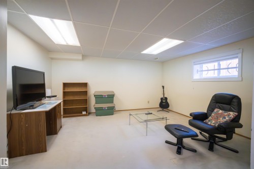 Finished room featuring a drop ceiling with integrated fluorescent lighting, a window with horizontal blinds, and light-toned walls - 4724 38B Avenue Nw, Edmonton, AB - Indoor Photo Showing Basement